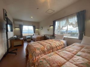 a hotel room with two beds and a window at Pension KUROSHIOMARU in Setouchi