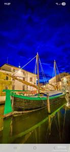a green boat sitting in the water at night at Salicornia Rooms in Comacchio