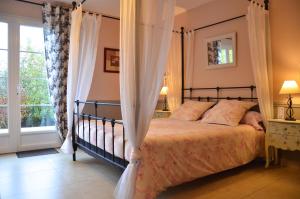 1 dormitorio con cama con dosel y ventana en La Villa Belle en Belle-et-Houllefort