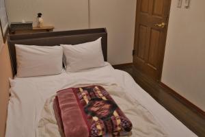 a bed with a blanket on top of it at IZA Kamakura Guest House and Bar in Kamakura
