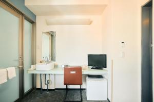 a bathroom with a sink and a desk with a computer at Urbain Hiroshima Executive in Hiroshima