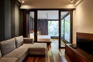 a living room with a couch and a bed at Wish Inn Silom - Decho Bangkok City in Bang Rak