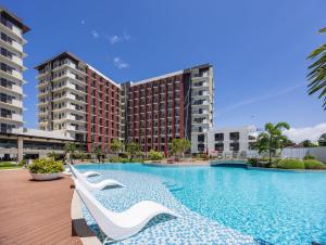 a swimming pool with white chairs in front of some buildings at Kajas Condo Luxe at Primeworld District near Mactan-Cebu International Airport in Lapu Lapu City