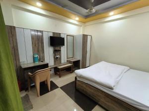 a bedroom with a bed and a desk and a television at HOTEL AMAN in Allahābād