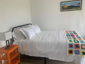 a bedroom with a white bed with a quilt on it at Spiller's Cottage in Twillingate +4 photos