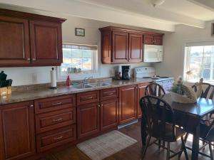 a kitchen with wooden cabinets and a table and a dining room at Salty B'y Cottage in Twillingate