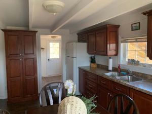 a kitchen with wooden cabinets and a white refrigerator at Salty B'y Cottage in Twillingate +15 photos