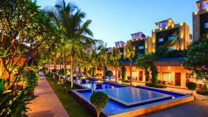 a pool in the middle of a courtyard with palm trees at Della Resorts in Lonavala