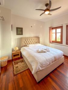 a bedroom with a large bed with a ceiling fan at Villa Maria Amalia in Tsagarada +51 photos