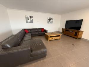 a living room with a leather couch and a flat screen tv at Karma on Compass in Edithburgh