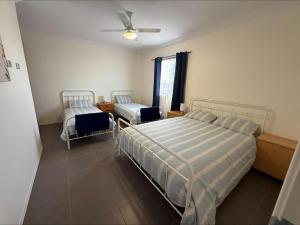 a bedroom with two beds and a ceiling fan at Karma on Compass in Edithburgh
