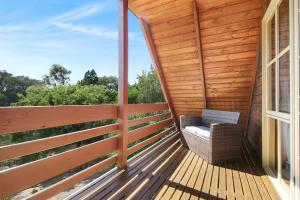 a wooden porch with a chair on a deck at The Nest Rustic Lodge-Style Hideaway in Beechworth