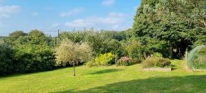 a garden with green grass and trees and bushes at Au Pré du Chêne in Le Faouët