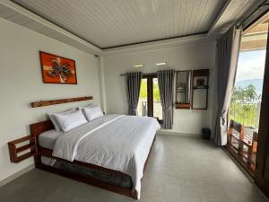 a bedroom with a large bed and a balcony at Toba Crest Vue in Parapat
