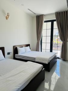 a bedroom with two beds and a large window at Green Hotel in Khánh Dương