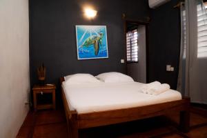 a bed in a room with a picture on the wall at Tiako Beach in Nosy Be