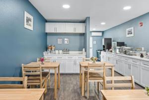 a restaurant with tables and chairs and a kitchen at Baymont by Wyndham Ocala Suites in Ocala