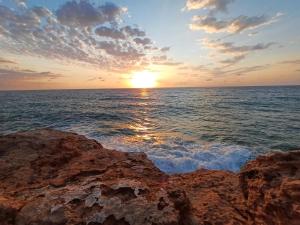 a sunset over the ocean with rocks in the water at Mona Baltico-Traveller Awards 2026 in Torrevieja