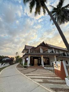 a building with palm trees in front of it at Sunin Hotel Dondet Riverside in Don Det