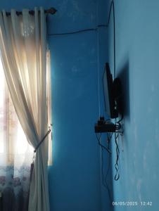 a blue room with a curtain and a television at Penginapan Verlo in Payakumbuh +8 photos