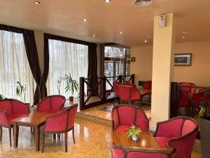 a waiting room with red chairs and tables and windows at Hotel OTDIH in Kavarna