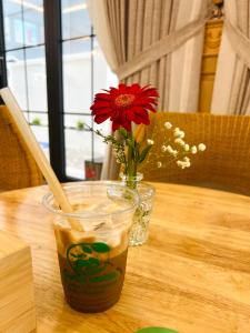 a vase with a red flower and a drink on a table at Green Hotel in Khánh Dương