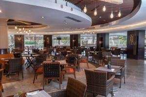 a restaurant with tables and chairs and windows at Mercure Convention Center Ancol in Jakarta