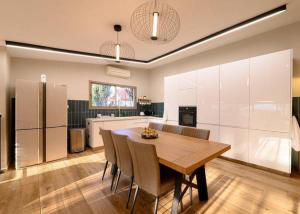 a large kitchen with a wooden table and chairs at אחוזת נופש ביער -ווילה עם בריכת ספא וזרמי עיסוי in Ma'alot Tarshiha