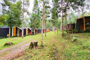a row of colorful tents in a forest with trees at Spekta Merbabu powered by Cocotel in Jlarem