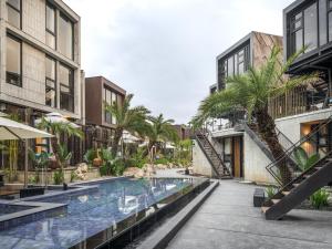 an outdoor swimming pool with palm trees and buildings at Deer Chaser Hotel - Sun Moon Lake in Yuchi