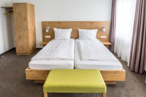 a bedroom with two beds and a green bench at Lahn Hotel in Biedenkopf