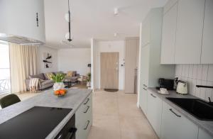 a kitchen with white cabinets and a living room at Apartament D&Z in Elblag