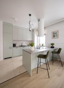 a kitchen with white cabinets and a island with two chairs at Apartament D&Z in Elblag