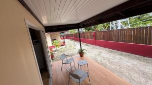a porch with two chairs and a table and a fence at Hiti Village G3 in Tikehau