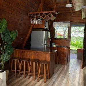 a kitchen with wooden walls and a counter with stools at Sol y Luna Chalet with volcano view and Jacuzzi in Fortuna