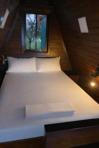 a white bed in a small room with a window at Sol y Luna Chalet with volcano view and Jacuzzi in Fortuna