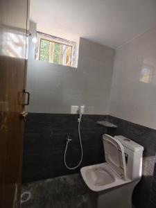 a bathroom with a white toilet and a window at Le DPS Viste in Rāyampālaiyam