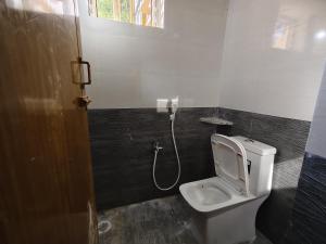 a bathroom with a white toilet in a room at Le DPS Viste in Rāyampālaiyam
