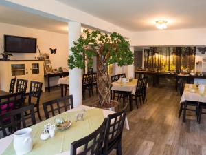 ein Restaurant mit Tischen und Stühlen und einem Baum in der Mitte in der Unterkunft Das kleine Hotel Lahnau in Lahnau