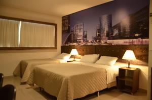 2 Betten in einem Hotelzimmer mit einem Bild an der Wand in der Unterkunft Hotel HortoPlaza in Hortolândia