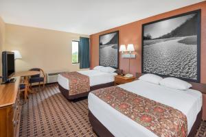 a hotel room with two beds and a flat screen tv at Super 8 by Wyndham Charleston Sikeston East MO in Charleston