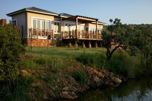 a house on a hill with a river in front of it at Mount Grace Hotel & Spa in Magaliesburg