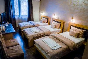a hotel room with three beds and a television at Villa Gurman 024 in Bačka Topola