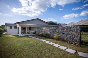 a house with a stone wall next to a yard at Salty Sands Studio in Rivière Noire