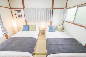 two beds in a room with two windows at Yokosuka Guest House in Yokosuka