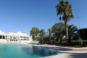 a swimming pool in front of a house with a palm tree at Hotel Masseria Marziale in Brindisi