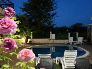 a swimming pool with white chairs and pink flowers at Апартхотел Созополски перли in Sozopol +43 photos