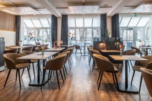 a restaurant with tables and chairs and windows at Hotel Raphael im Allgäu in Kempten