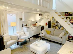 a living room with white furniture and a staircase at Gezellig Cottage Markdal met gratis fietsen in Breda