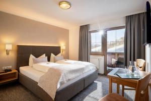 a hotel room with a large bed and a desk at Appartements Metzgerhof in Niederau